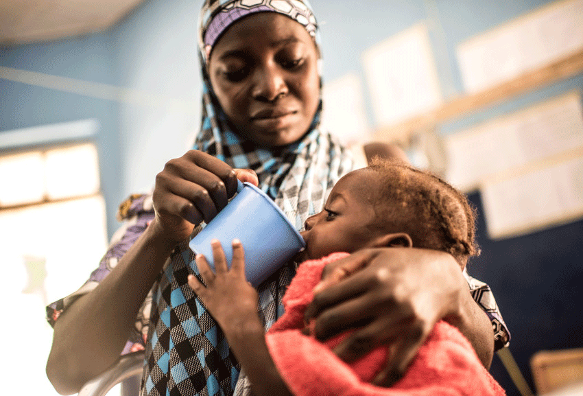 Rakiya feeding her daughter, Saliyha, therapeutic milk at a Save the Children stabilisation centre in Nigeria.